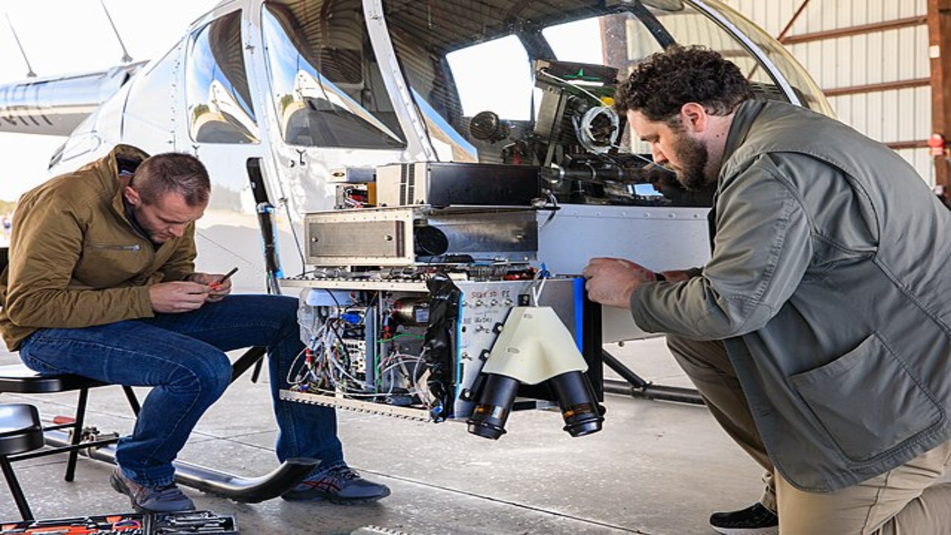 Two engineers working on navigation system of Nova-C in front of a helicopter
