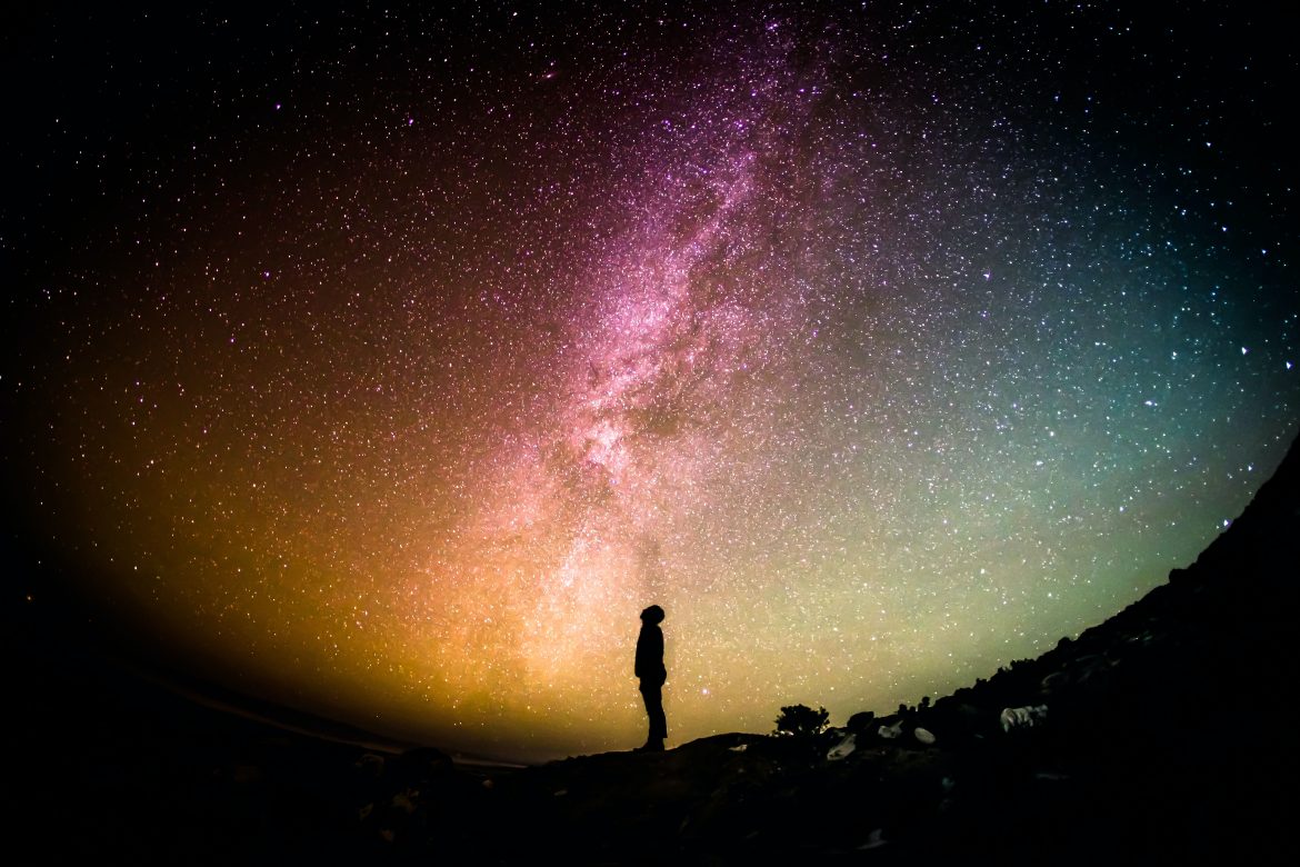 A person standing on a hill with stars in the sky